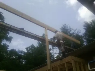 Carpenter setting a ridge beam over a new addition frame — Ice Dam Removal by Roofing Brothers in Midway