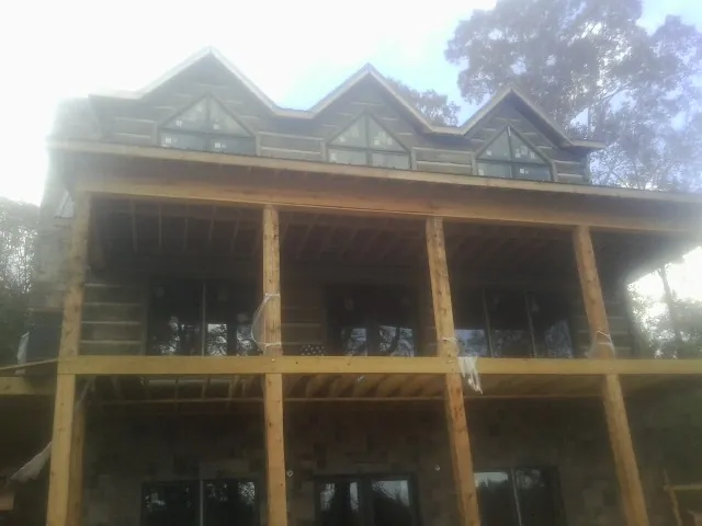 Dormers and porch framing on a large log home under construction — Roof Coating work by our crew in Midway