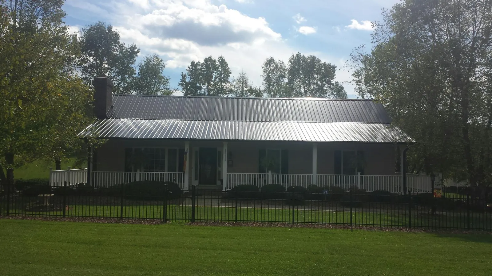 Gray metal roof on a brick ranch with a full width front porch — Gutter Guard Installation work by our crew in Midway